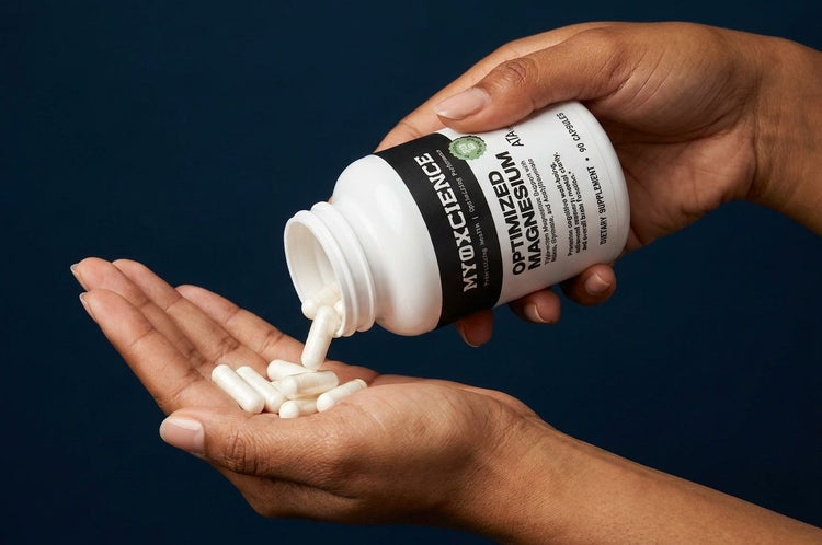 A hand pouring Optimized Magnesium capsules from the bottle into the other hand